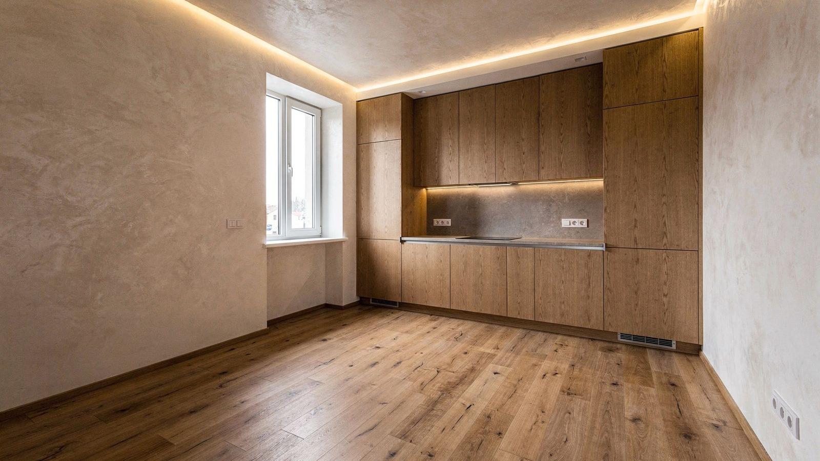 Living room of a renovated Podil apartment with oak flooring, lime plaster walls and a cove-lit ceiling